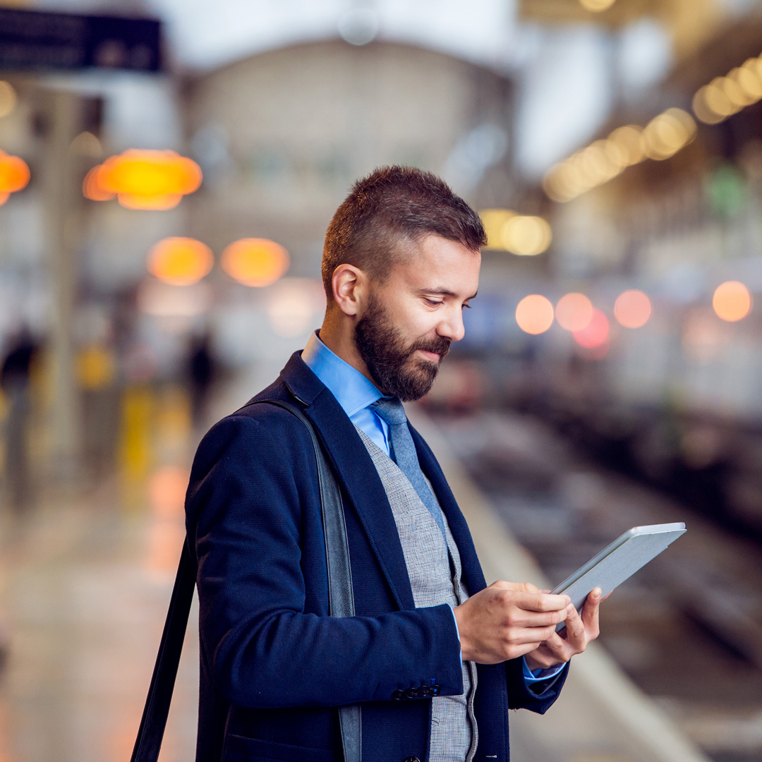 business man at train station looking at tablet