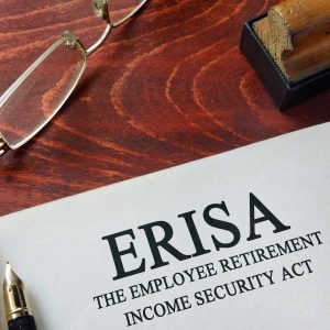 a piece of paper that displays the letters ERISA with a pen and a pair of glasses beside it