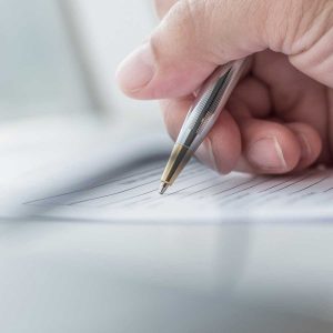 employer writing on a form with a pen. close up of hand and form