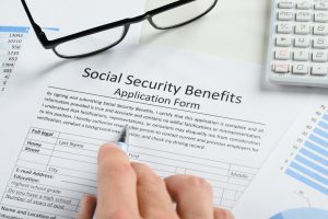 Hand Holding Pen Over Social Security Benefits Form