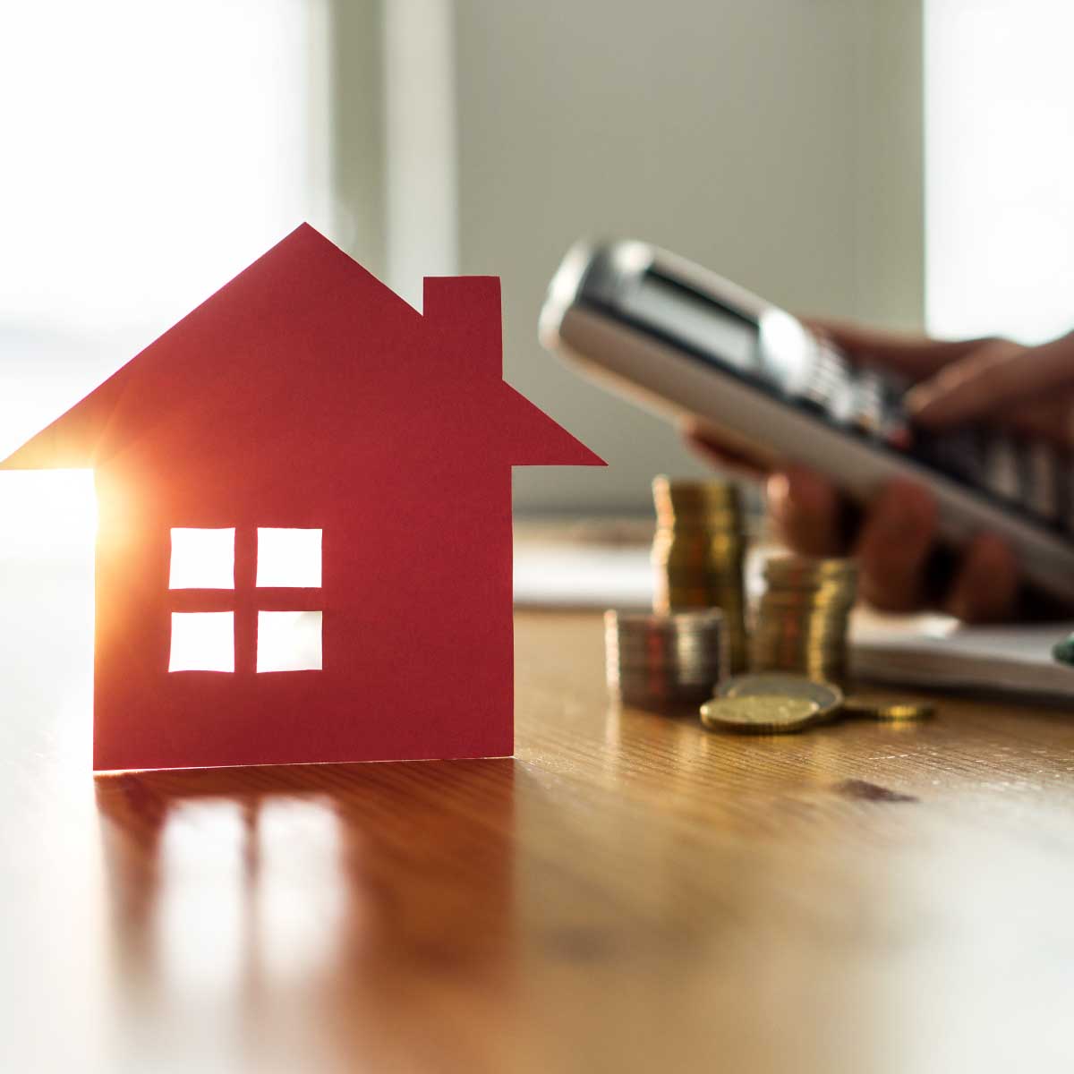 paper house next to person using calculator