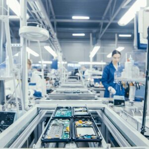 an Electronics Factory Workers Assembling Circuit Boards by Hand While it Stands on the Assembly Line. High Tech Factory Facility.