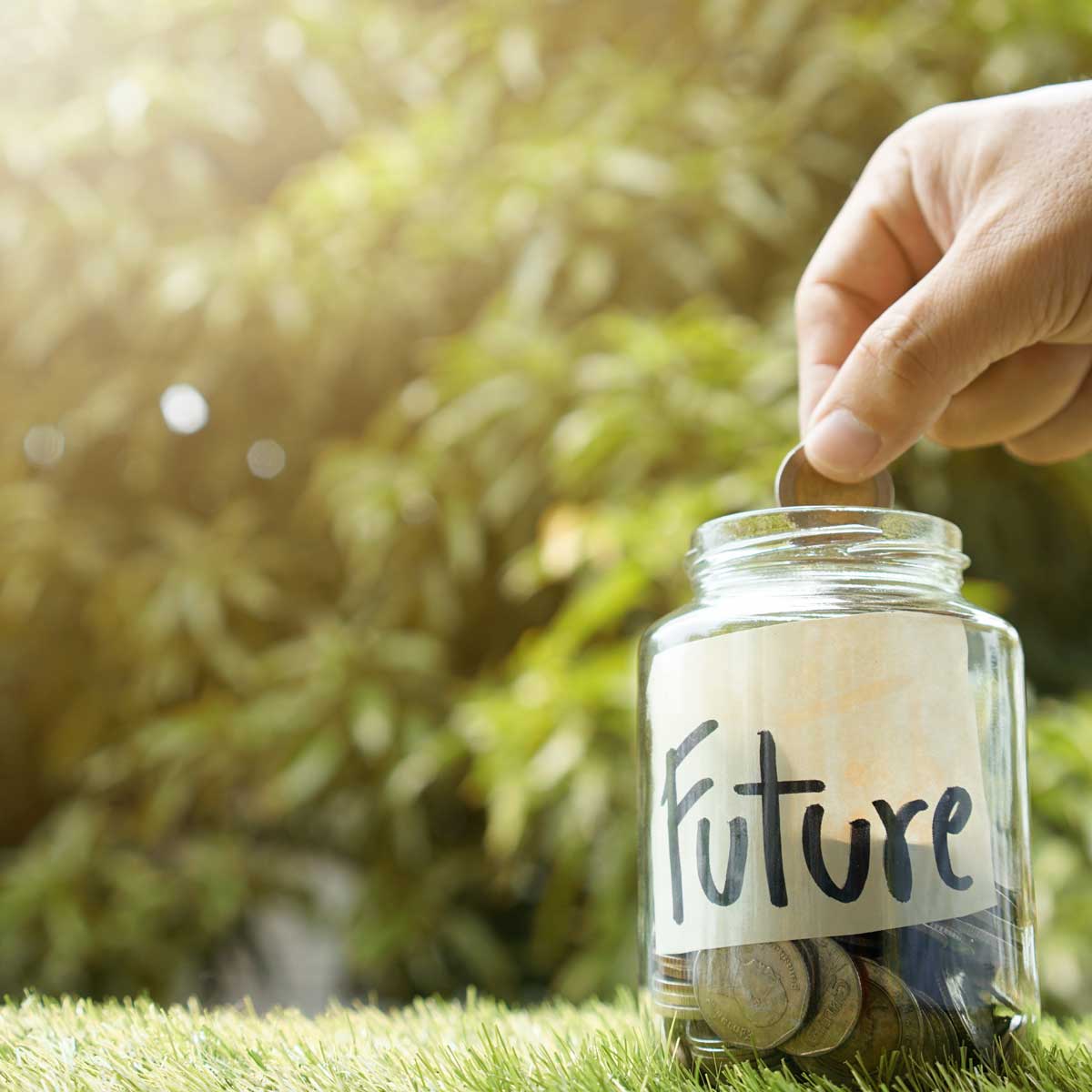 Money saving, Hand putting coin in glass jar with coins inside For now and future money. Concept of saving money for future.