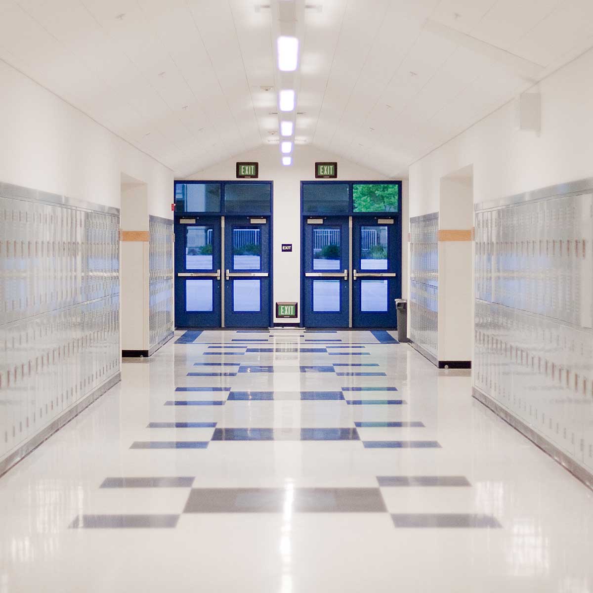 School Hallway with lockers on walls and blue doors to outside