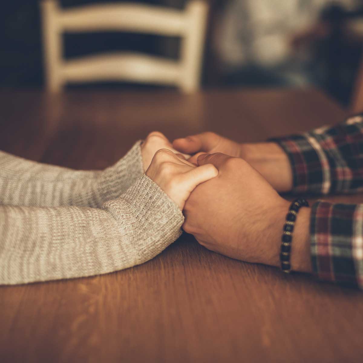 Couple in love holding hands in a cafe. Focus on hands.