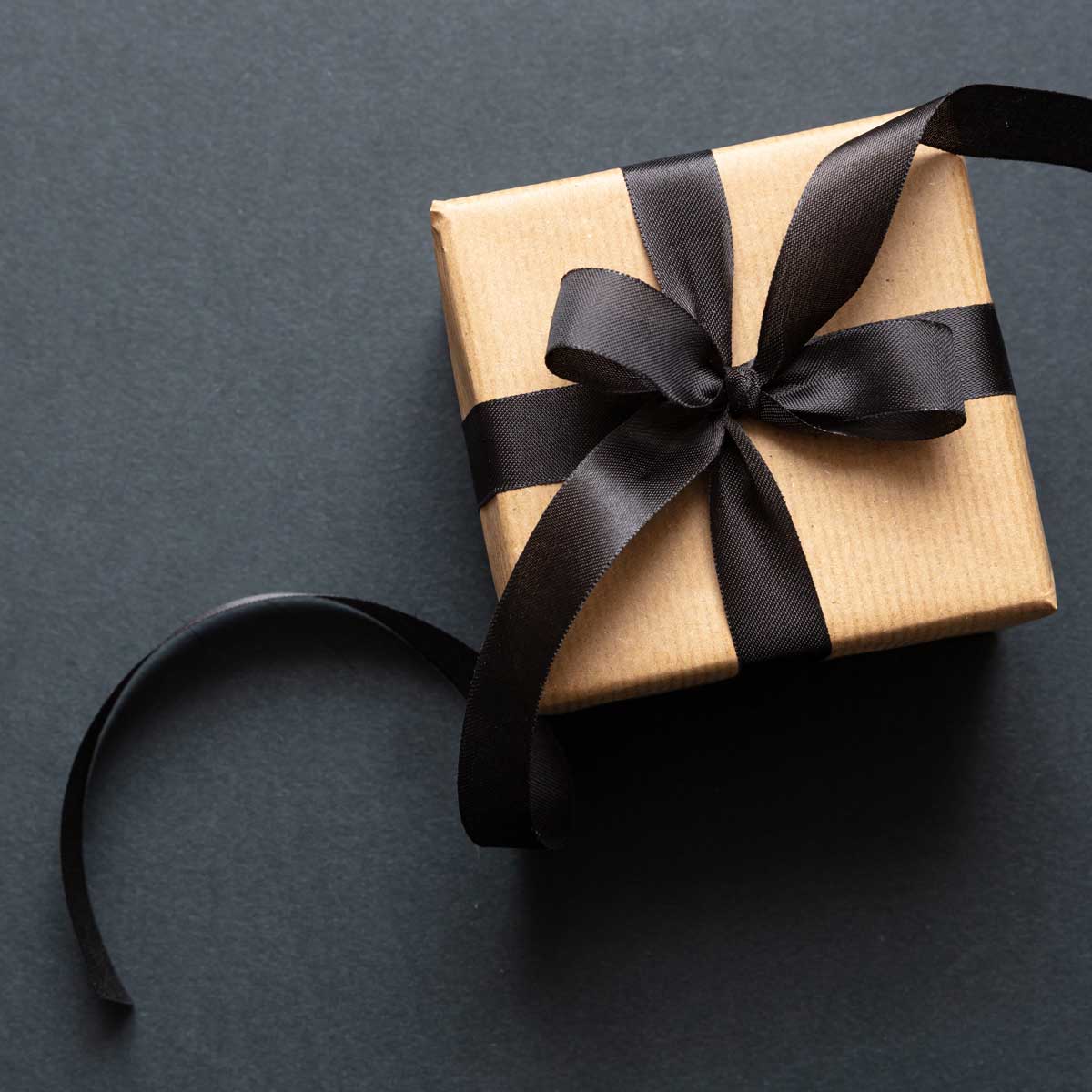 Gift box with black ribbon against black background