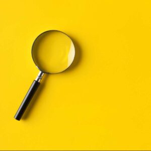 Magnifying glass on a mustard yellow background
