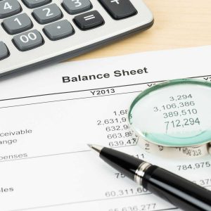 Balance sheet financial report with magnifier, pen, and calculator