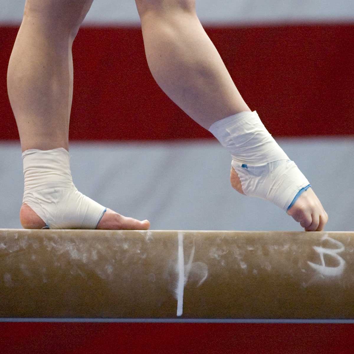 Closeup of a gymnast's feet with chalk and protective equipment in a gymnastics competition.