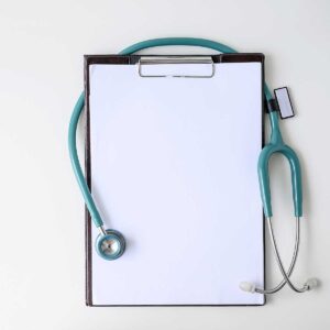 Blank medical clipboard with stethoscope on white background.