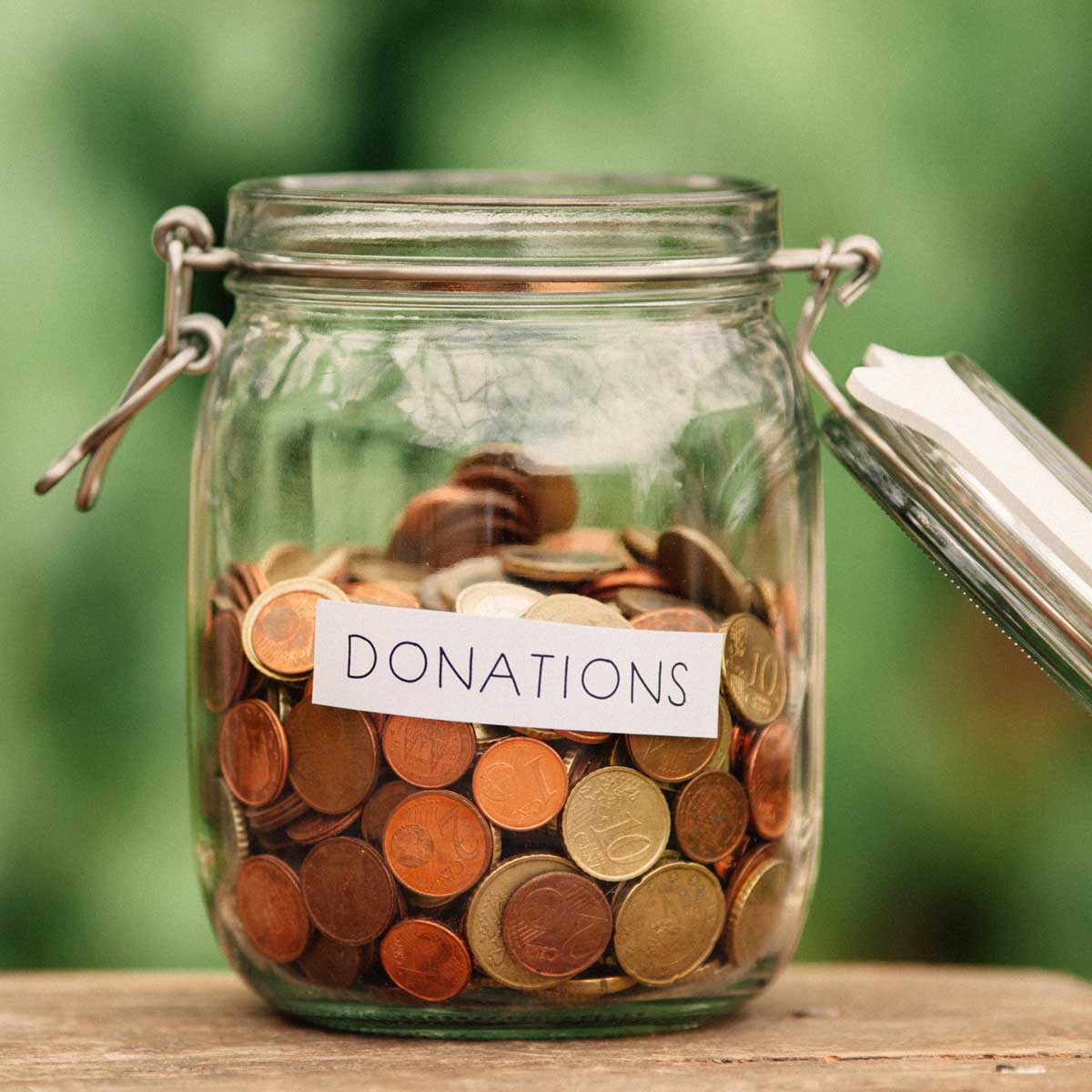 Glass jar with coins and change piled up. label of donations across front of jar