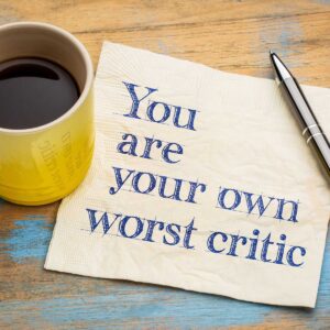 coffee mug with pen and paper saying you are your own worst critic