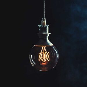 Vintage lightbulb hanging from string on dark background; idea imagery