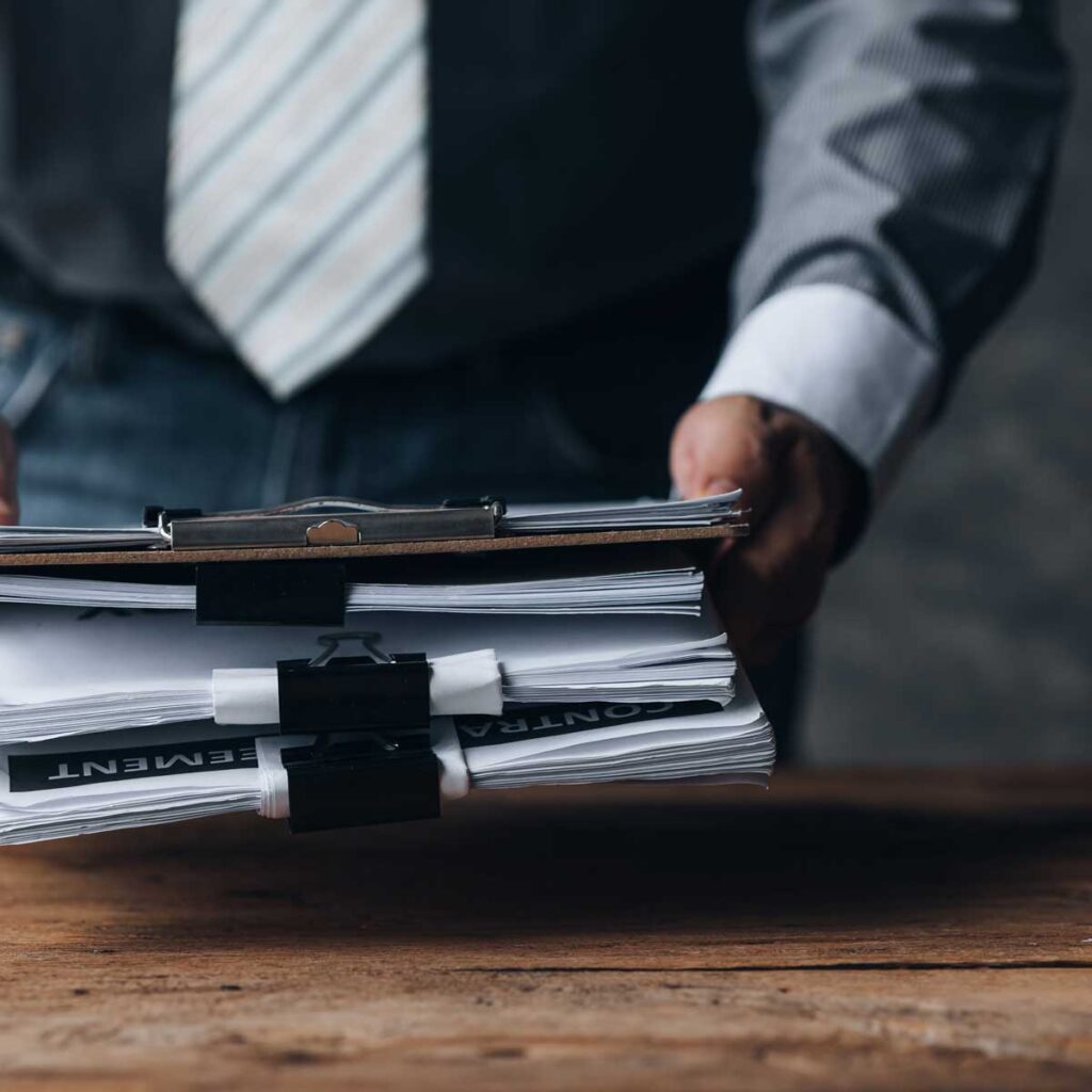 professional-with-stack-of-documents-and-clipboards;-focus-on-papers-and-businessman's-hands