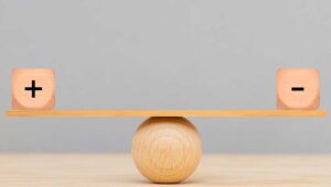 plus and minus wooden tiles balancing on a wooden plank atop a wooden ball; balancing