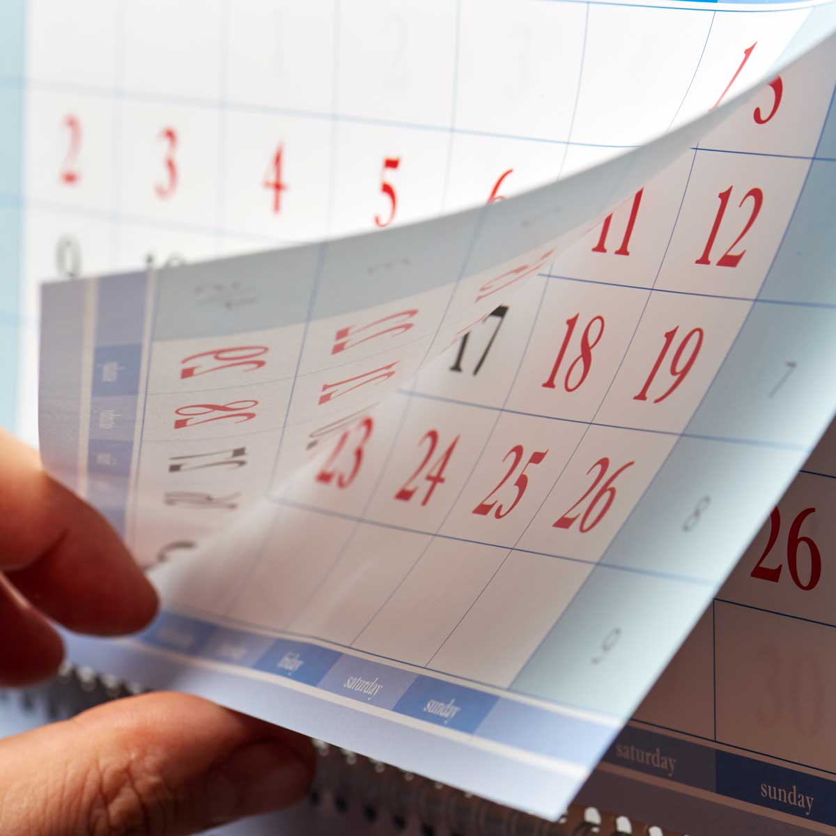 Hand-flipping-through-sheets-of-wall-calendar
