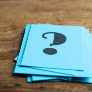 Blue-paper-cards-with-question-mark-on-wooden-background,-closeup
