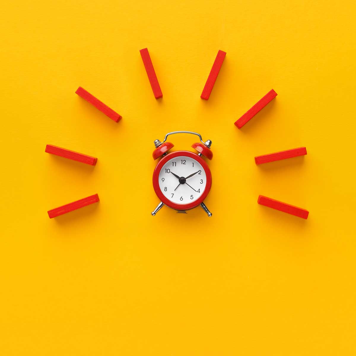reminder-and-approaching-deadline-imagery.-Alarm-clock-with-red-dominoes-on-yellow-background