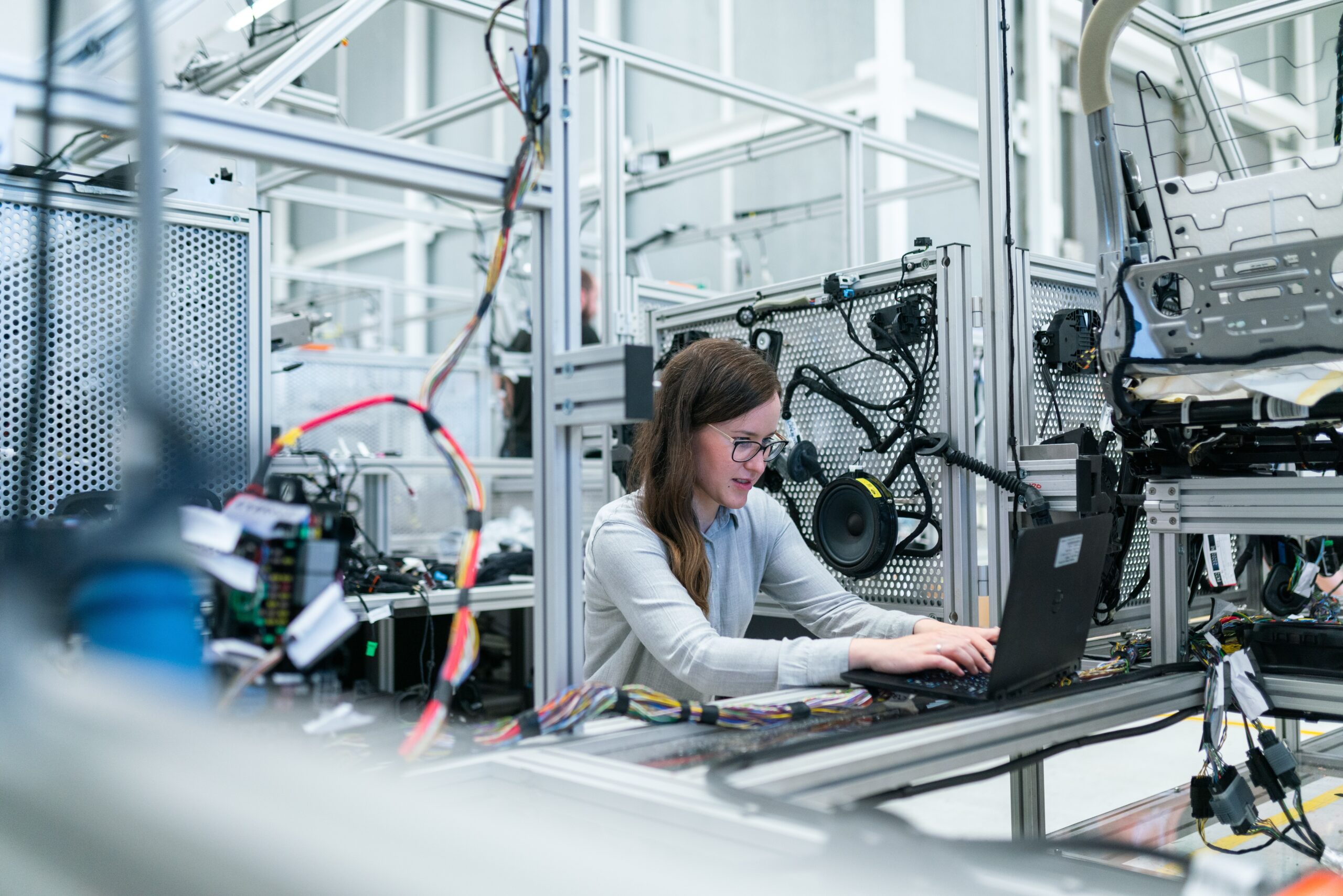Woman working on computer in tech manufacturing atmosphere.